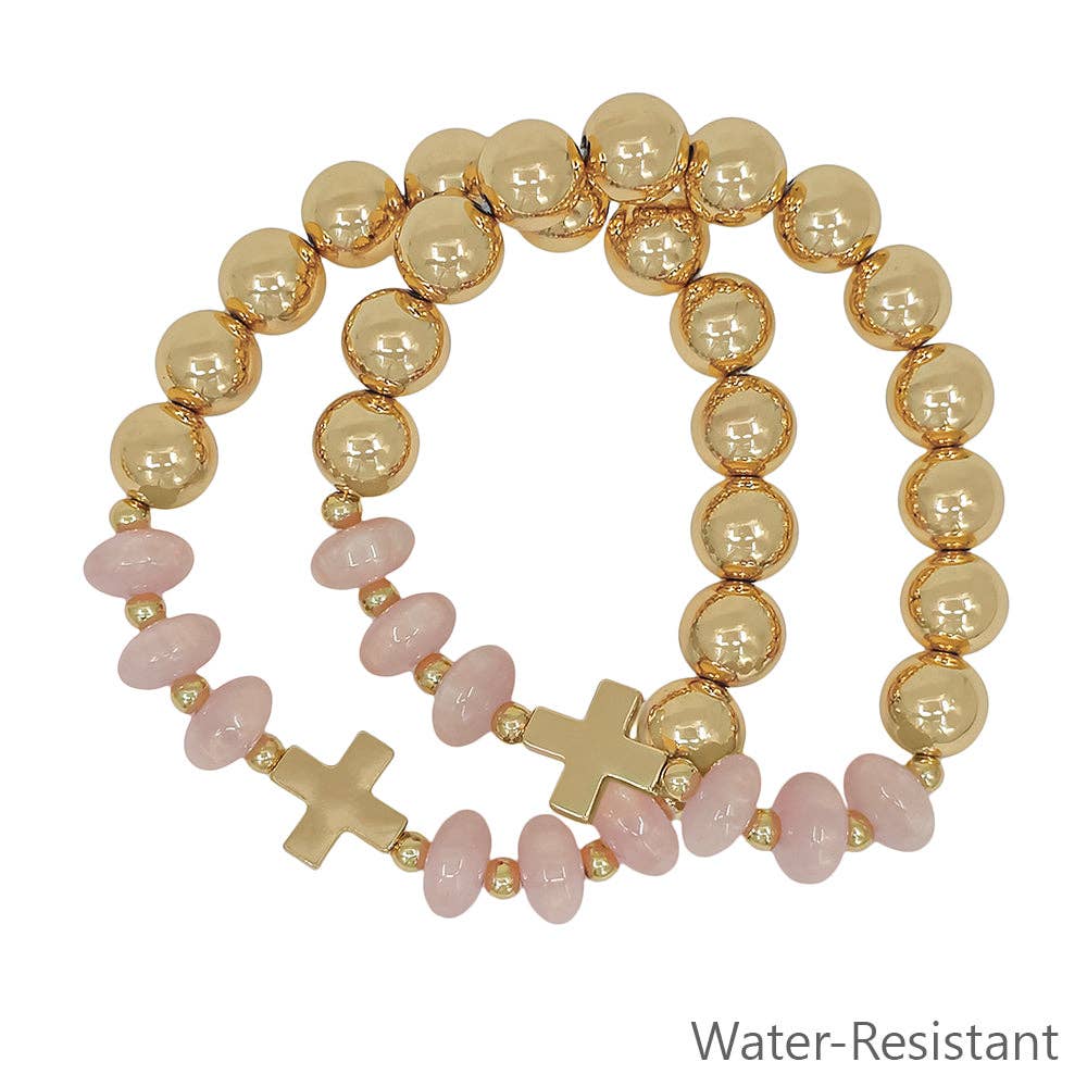 Gold and pink beaded bracelet with cross charms on a white background
