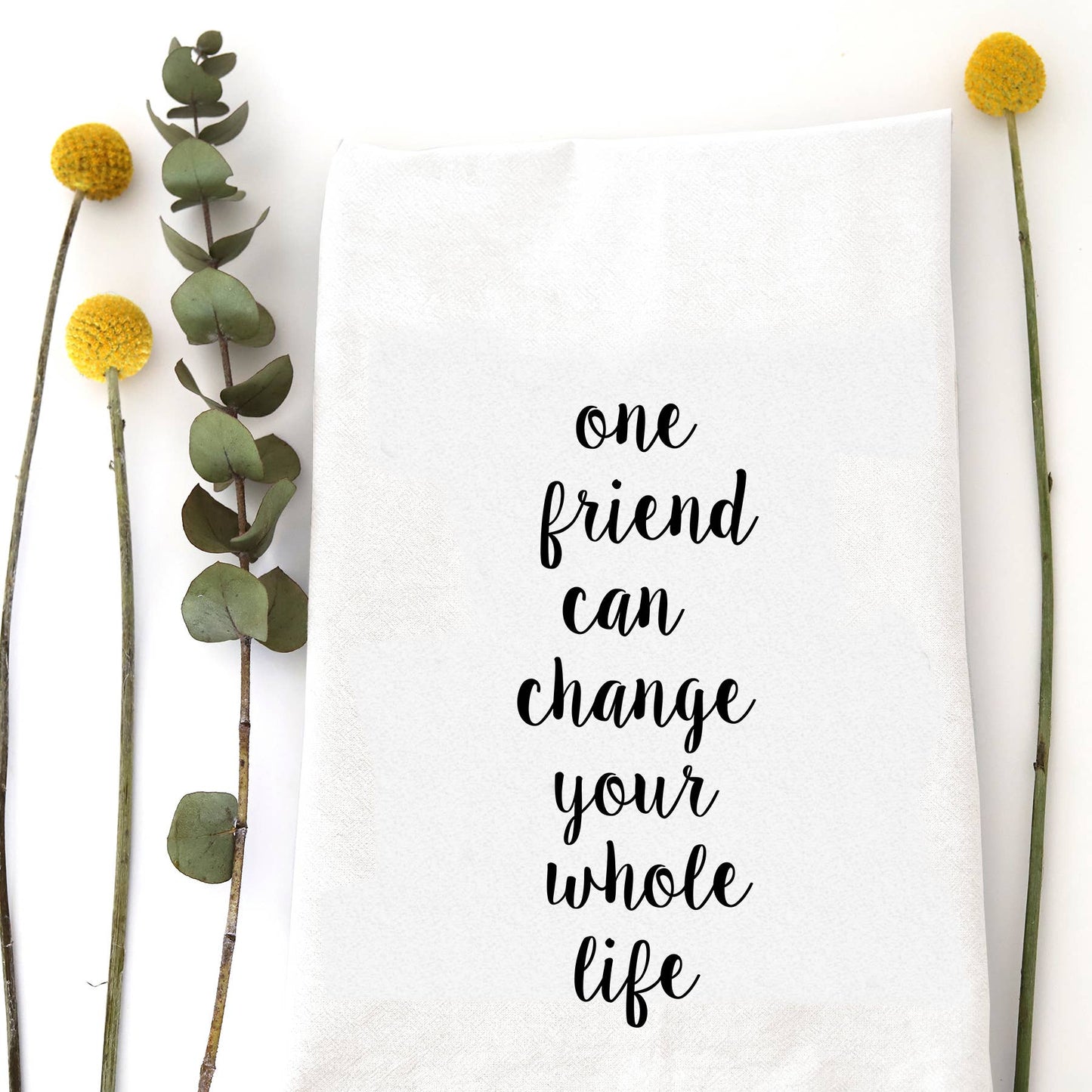 White cotton flour sack tea towel featuring the sentimental quote "One friend can change your whole life" in elegant black script.