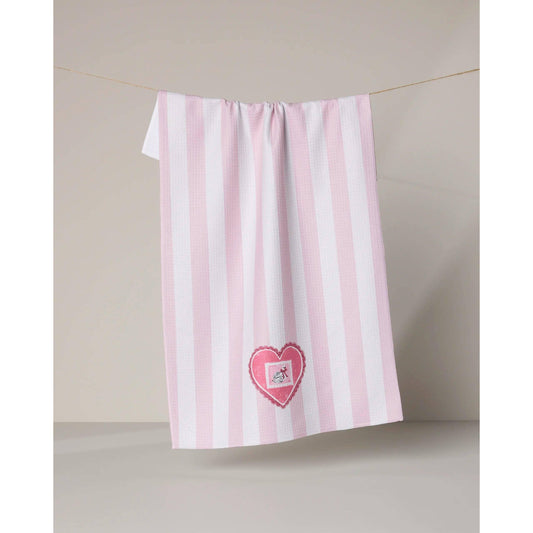Pink and white striped towel with a heart design hanging on a line against a beige wall.