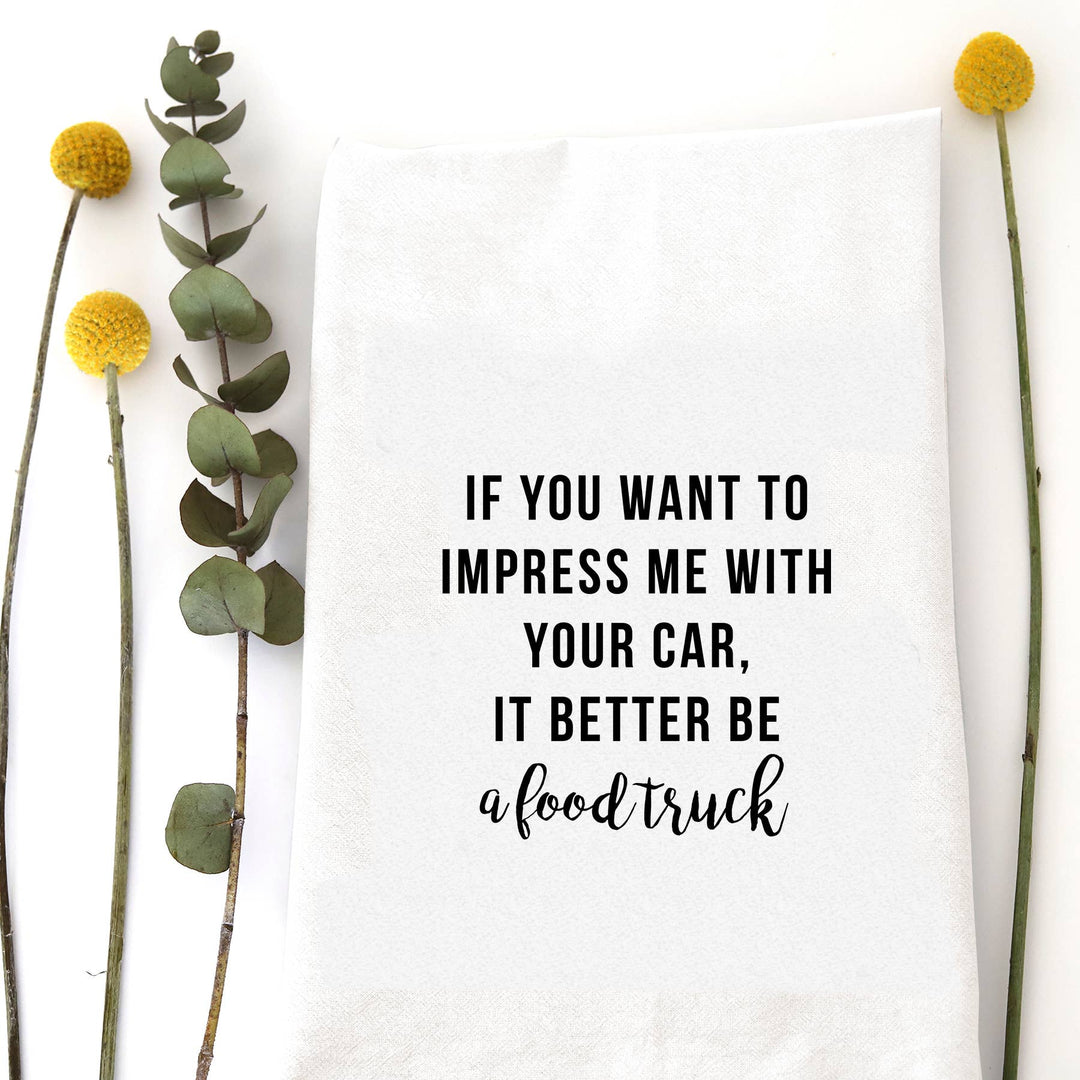 White cotton flour sack tea towel with the phrase "If you want to impress me with your car, it better be a food truck" in black typography.