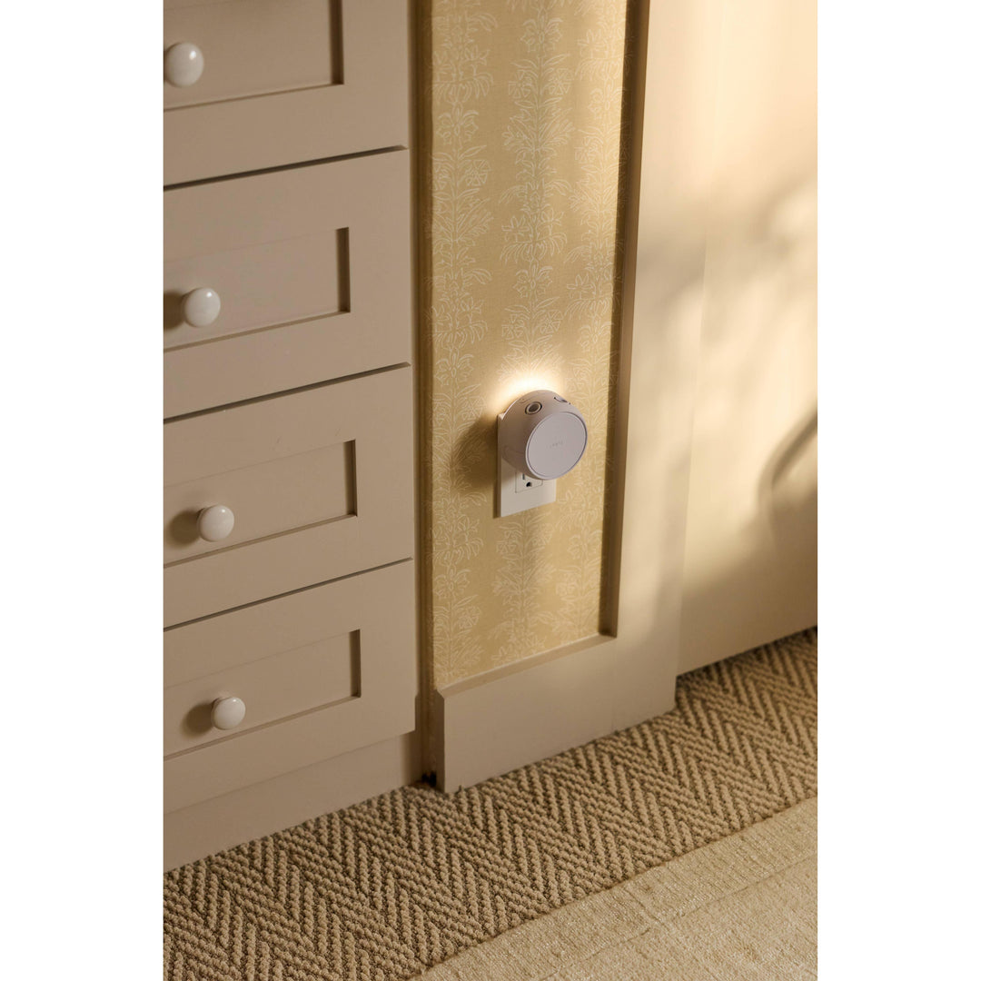 Pura Home diffuser plugged into a low outlet beside wood cabinets