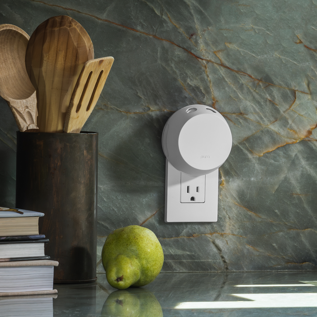 Pura Home smart fragrance diffuser in a kitchen outlet next to cooking utensils