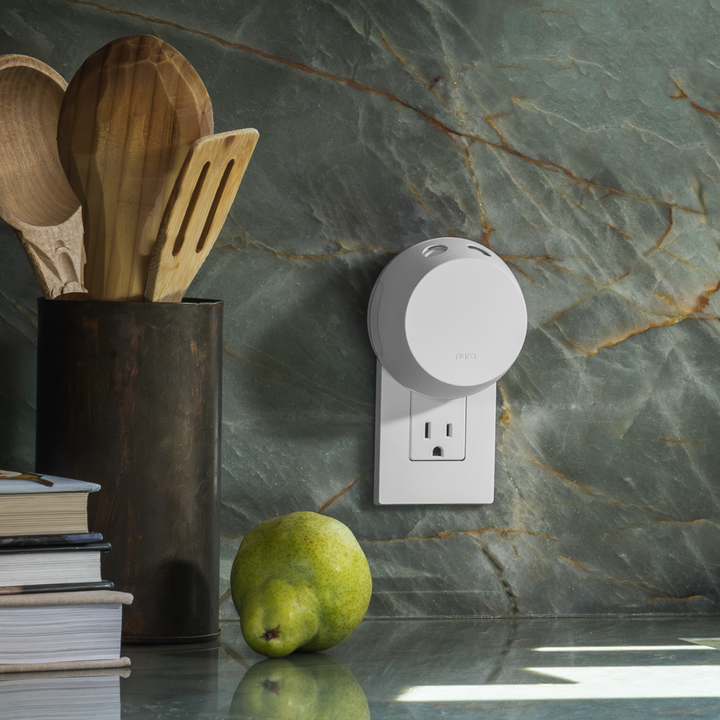 Pura Home smart fragrance diffuser in a kitchen outlet next to cooking utensils