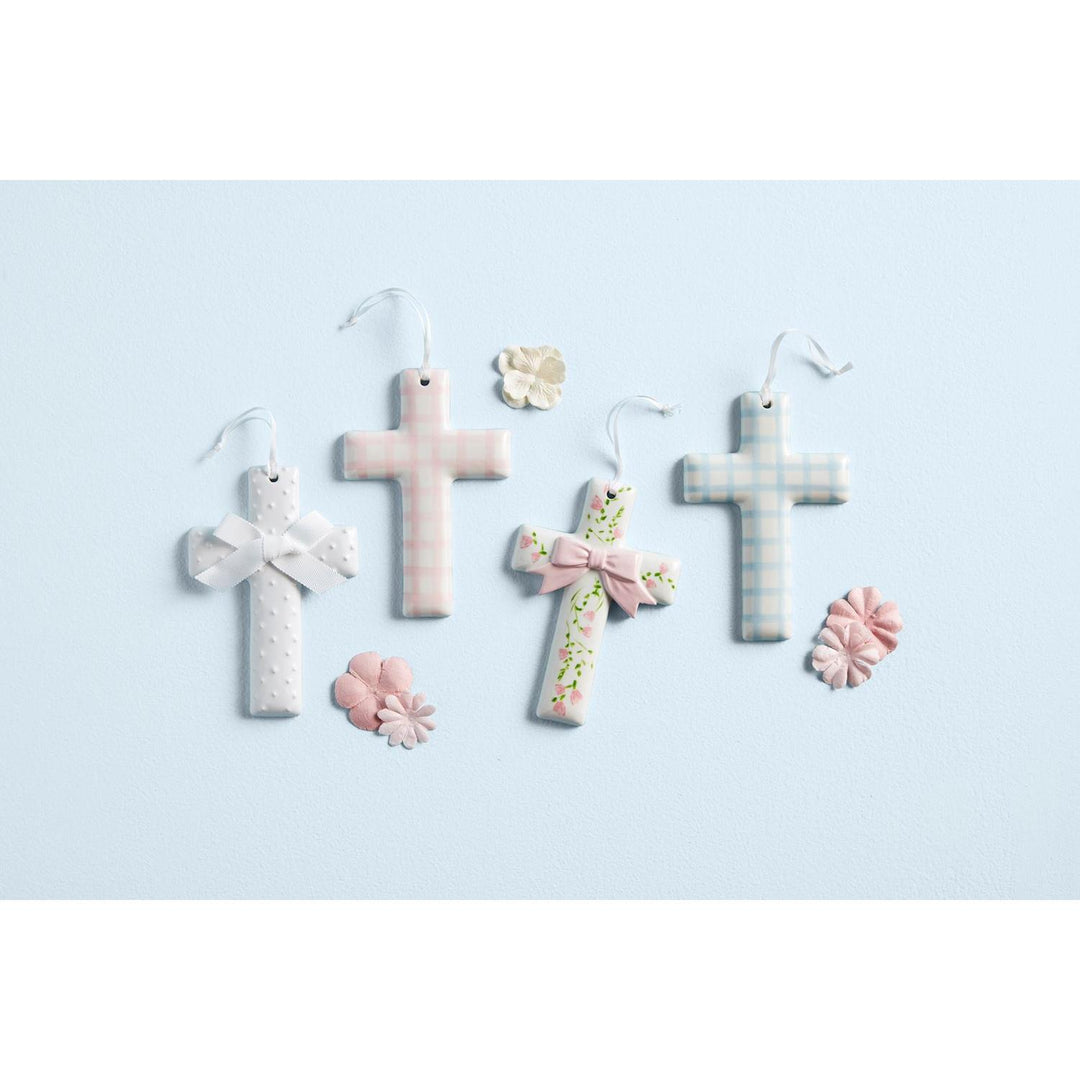 Hand-painted Mud Pie ceramic crosses featuring delicate ribbon hangers, displayed in a cotton rope basket.