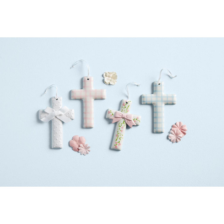 Hand-painted Mud Pie ceramic crosses featuring delicate ribbon hangers, displayed in a cotton rope basket.