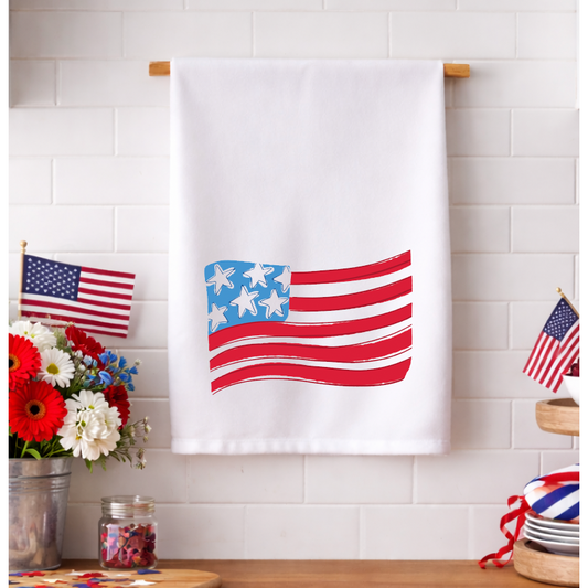 Waving American Flag tea towel with a vibrant red, white, and blue print hanging in a kitchen.