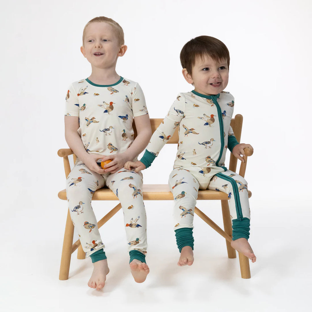 Unisex bamboo baby romper with yellow duck print on a light blue background