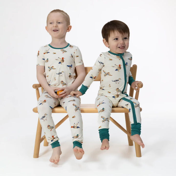 Unisex bamboo baby romper with yellow duck print on a light blue background
