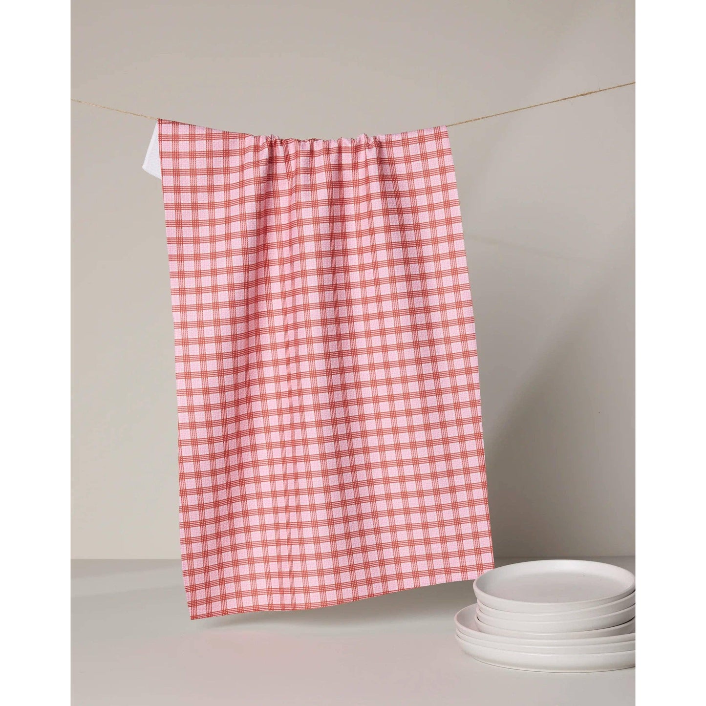 Red and white checkered towel hanging on a line with plates below.