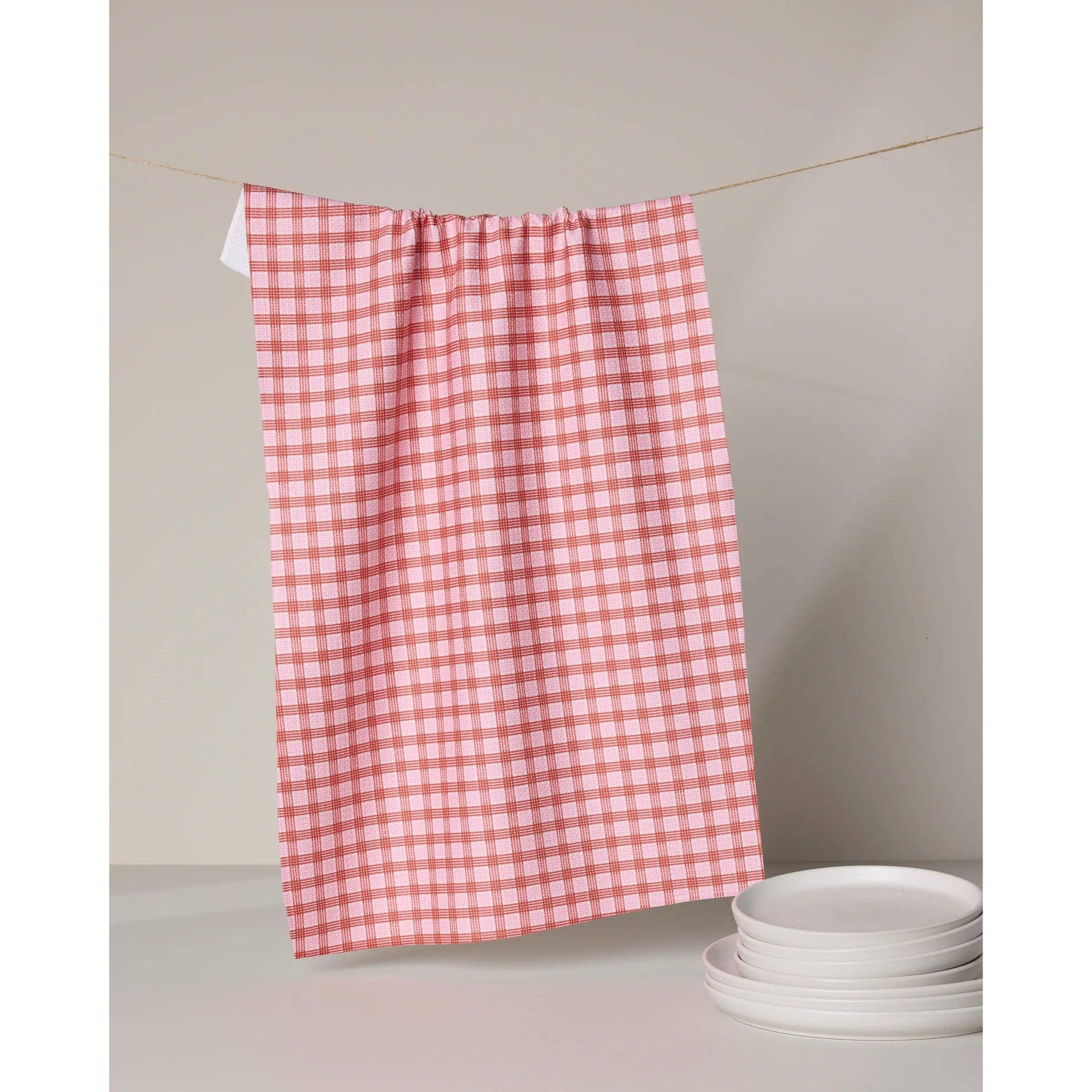 Red and white checkered towel hanging on a line with plates below.