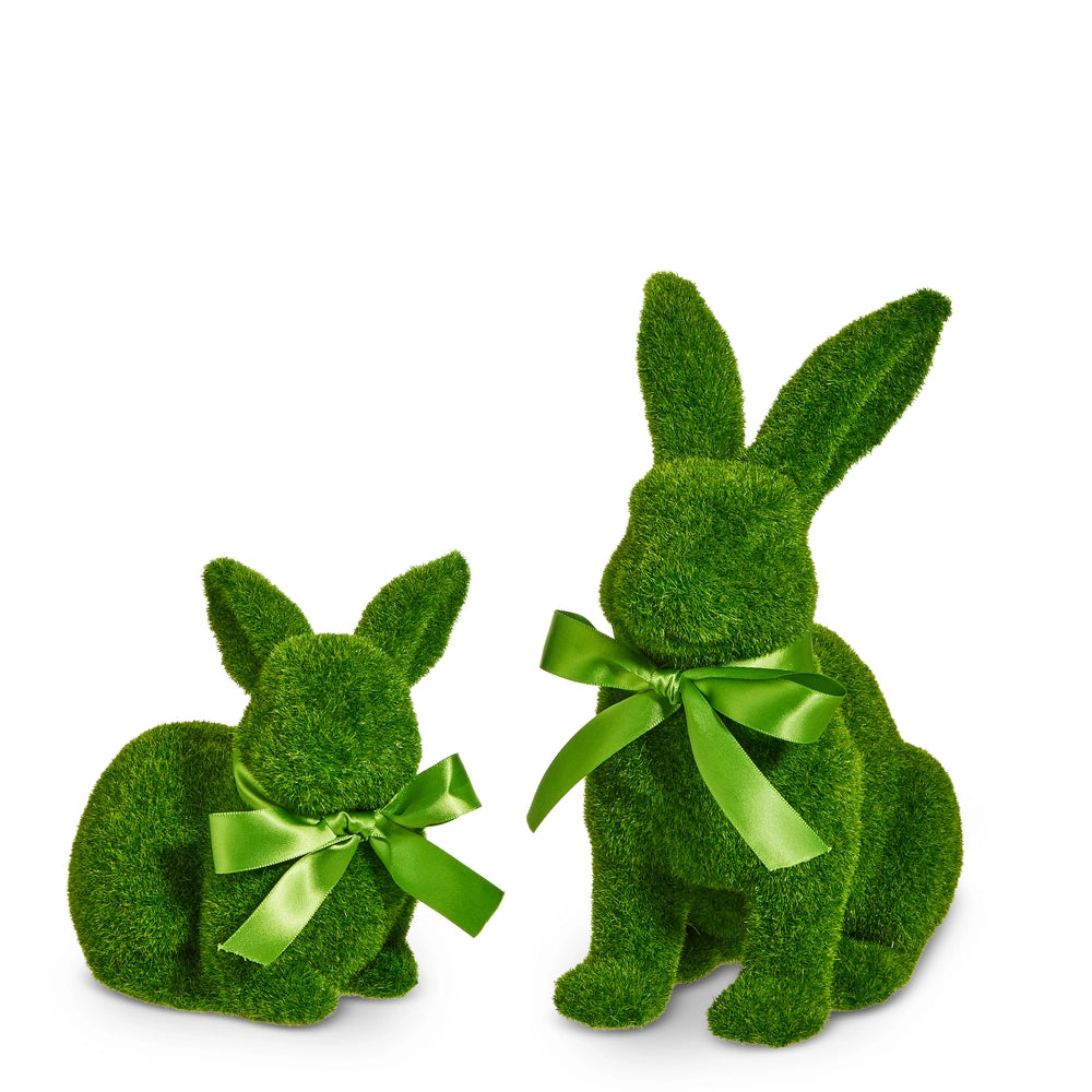 Two green moss-covered bunny figurines with green ribbons on a white background