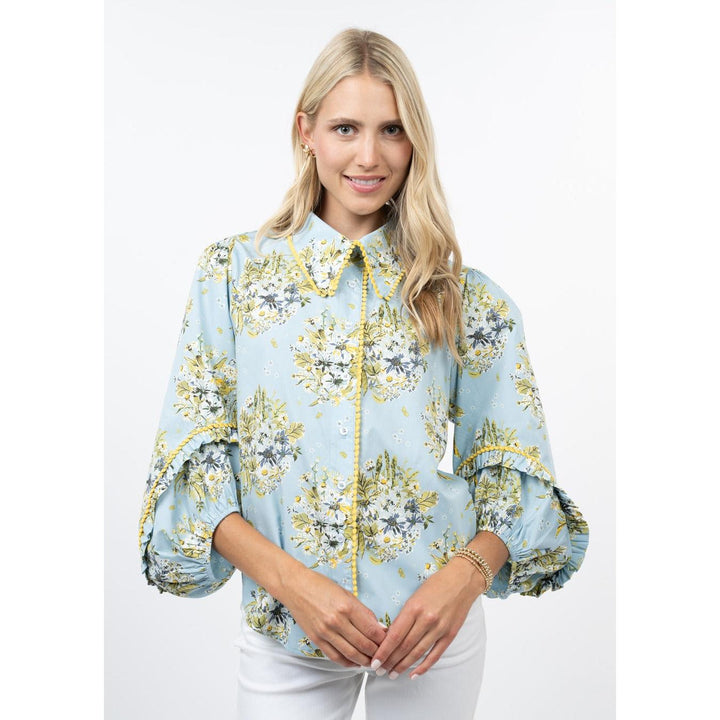 Woman wearing a light blue floral blouse with yellow accents on a white background