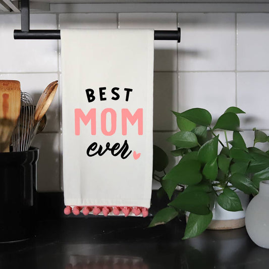 White cotton flour sack tea towel with "BEST MOM EVER" printed in bold black text and a pink pom-pom trim.