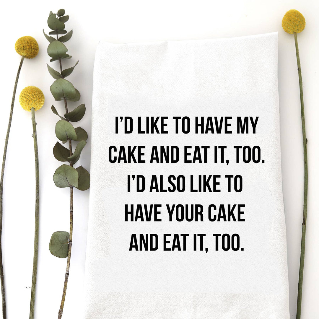 White cotton flour sack tea towel featuring the funny quote "I'd like to have my cake and eat it, too..." in bold black typography.