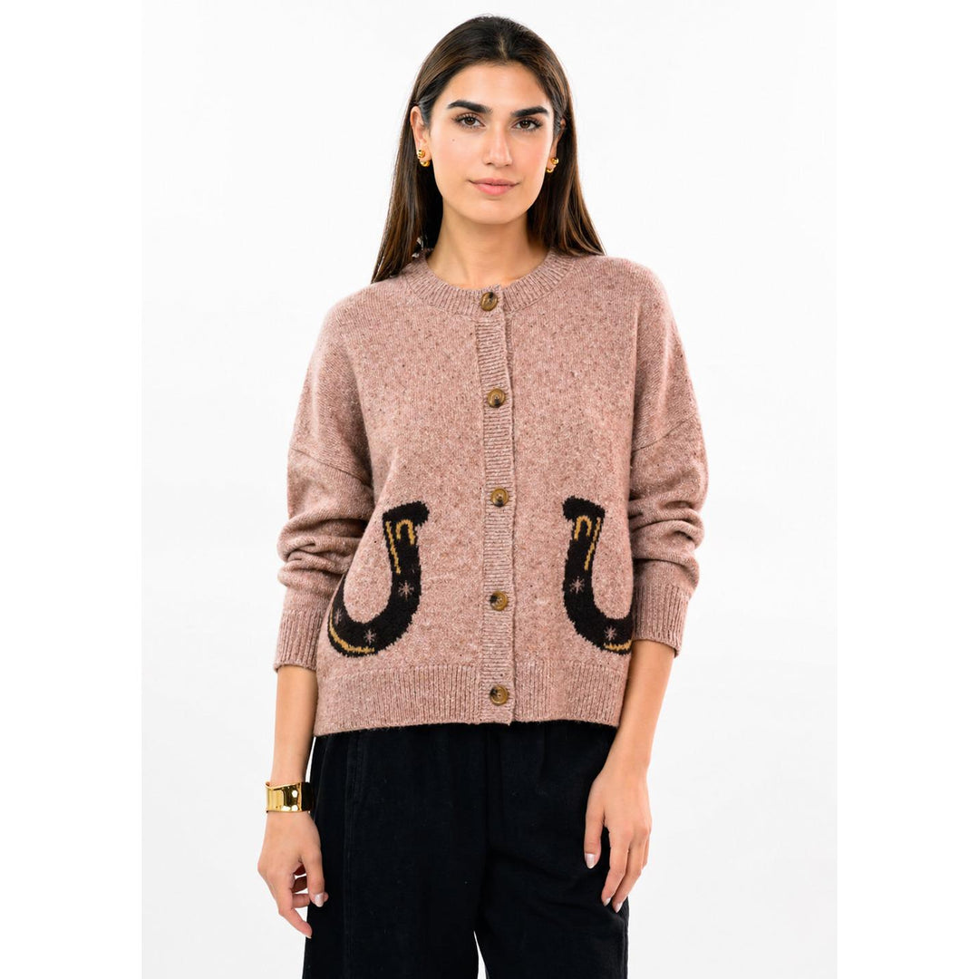 Model wearing the rose pink Ivy Jane Horse and Horseshoe sweater styled with dark pants.