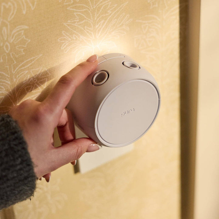 Hand placing the Pura Home V5 diffuser into a wall outlet