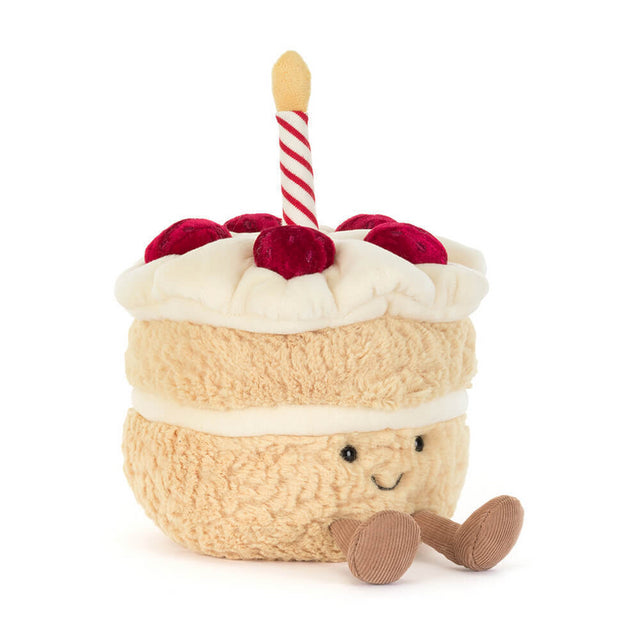 Jellycat Amuseables Birthday Cake plush toy showcasing its cream-colored tussly fur, plush strawberries, striped candle, and brown corduroy feet.