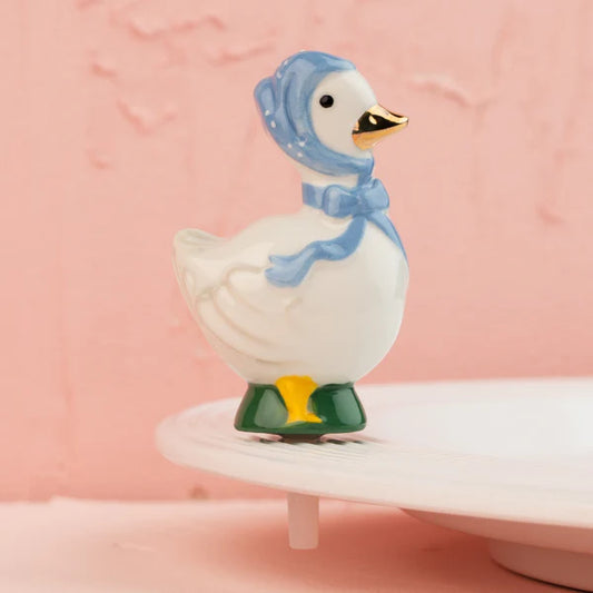 Nora Fleming Porch Pal mini featuring a white ceramic goose wearing a blue bonnet and orange beak.