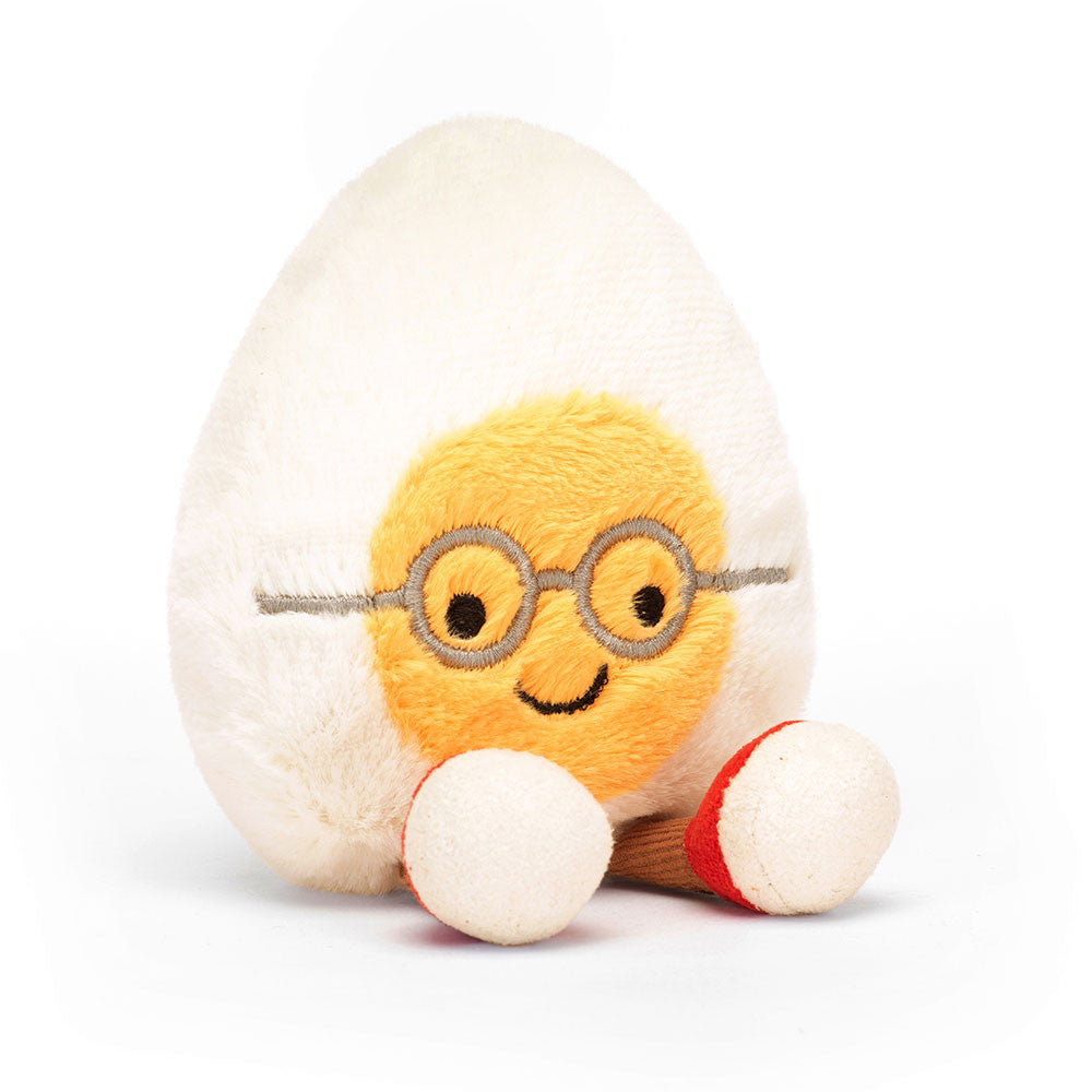 Jellycat Amuseables Boiled Egg Geek plush toy showcasing its white and yellow textured body, black glasses frames, and small backpack.