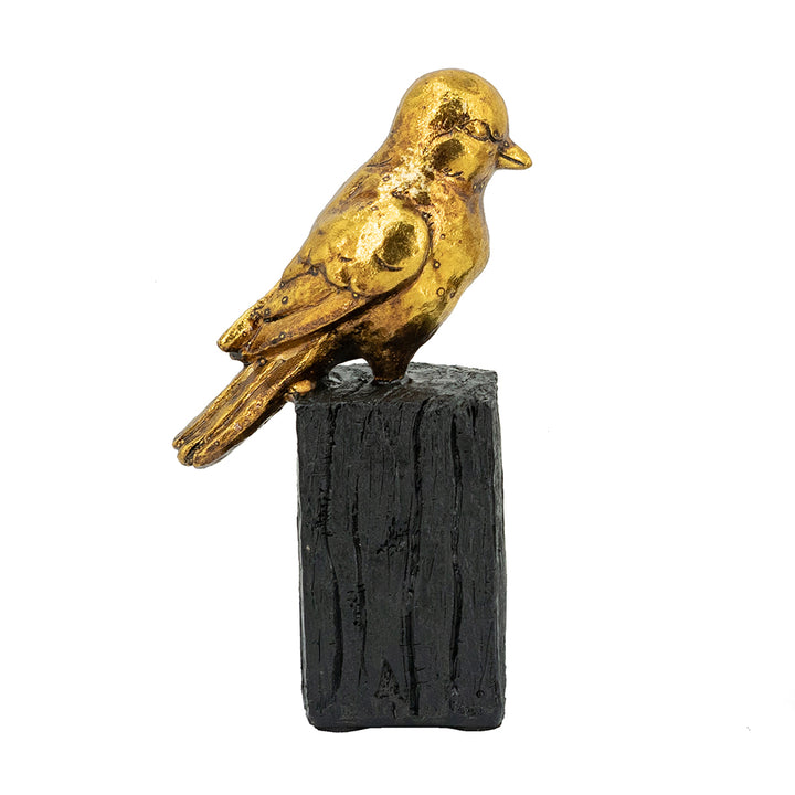 Gold bird figurine on a black cylindrical base against a white background