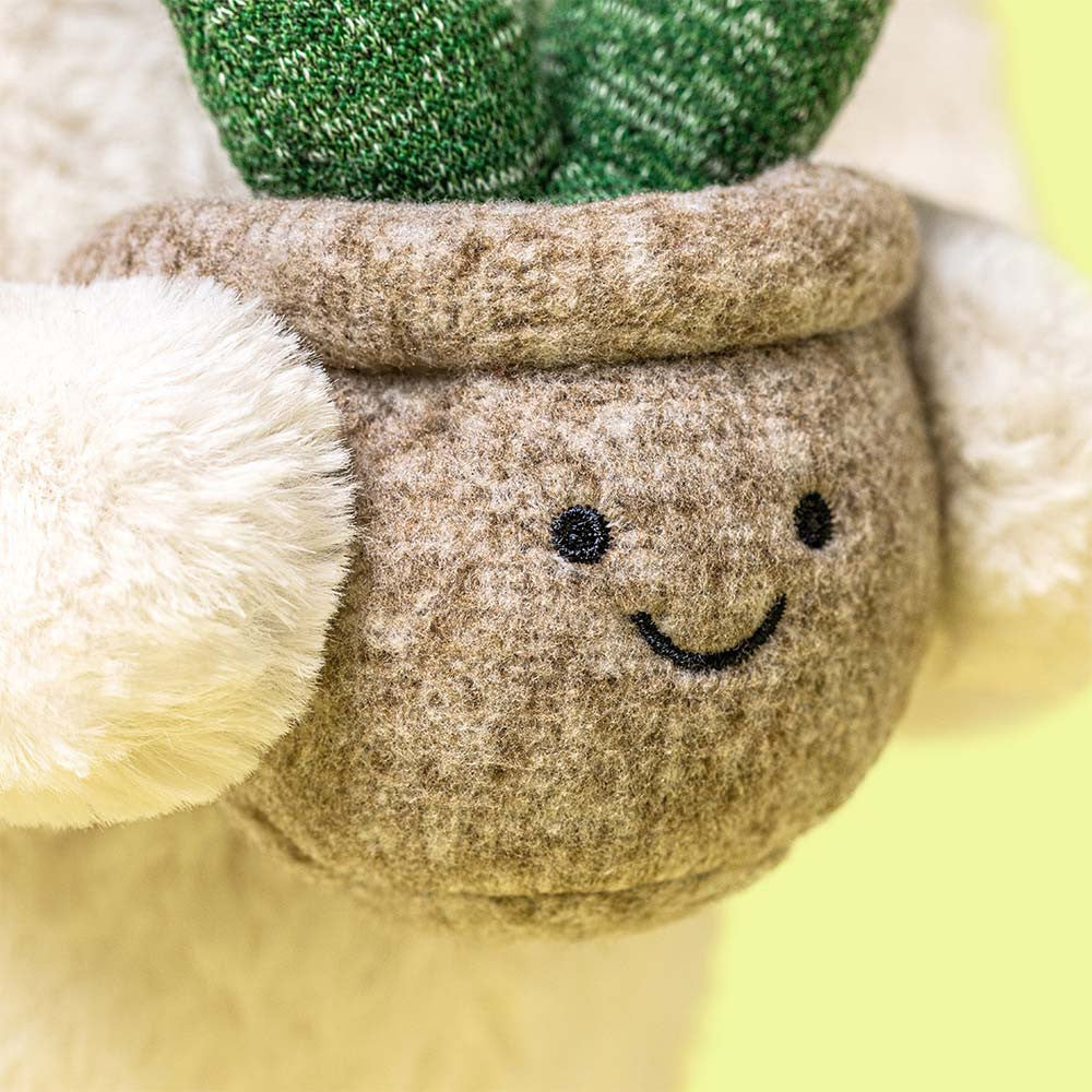 Close-up of the Jellycat Cream Bunny’s face and the textured plush leaves of her plant companion.