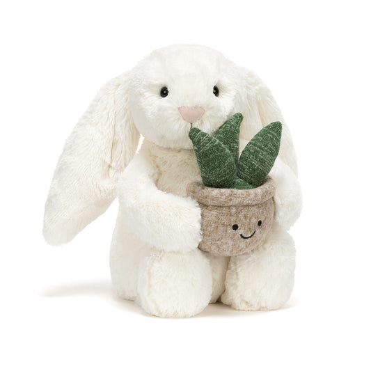 Jellycat Bashful Cream Bunny holding a small plush plant with a smiling face in a soft pot.