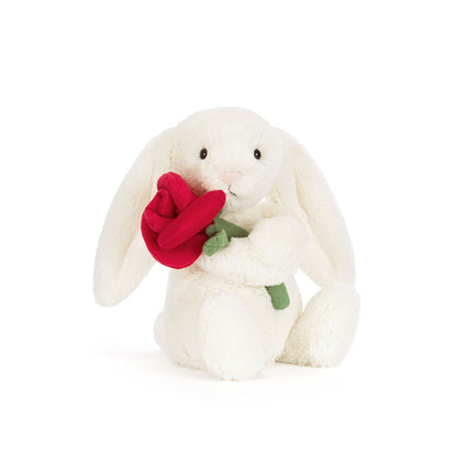 White plush bunny holding a red rose on a white background