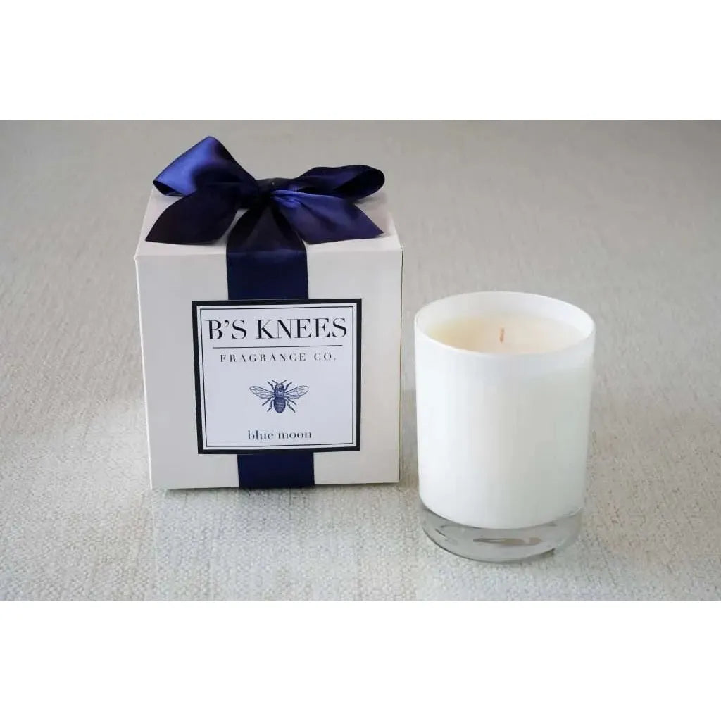 White candle with a blue ribbon and box labeled 'B'S Knees Fragrance Co' on a light gray background