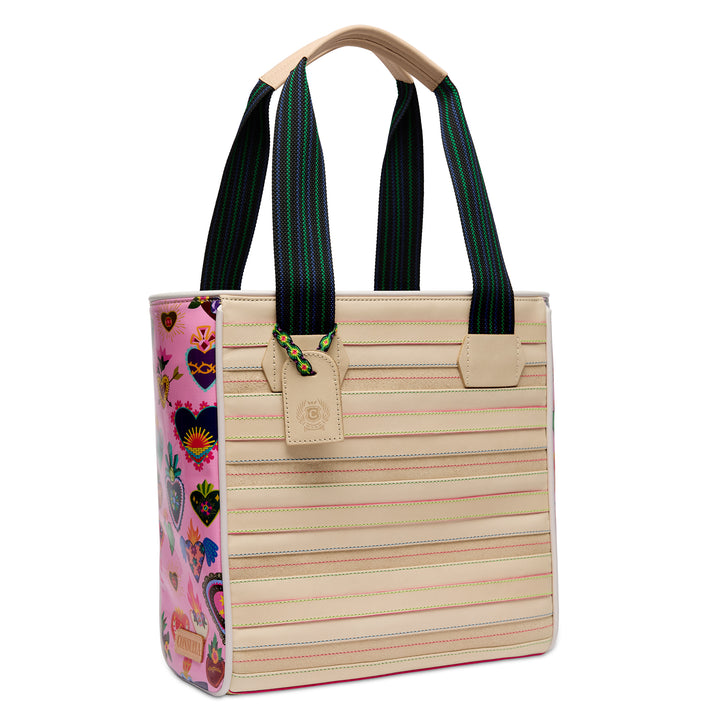 Three-quarter angled view of the Consuela Caroline Classic Tote showing the cream stitched front, pink folk-art heart side panel, and leather hangtag.