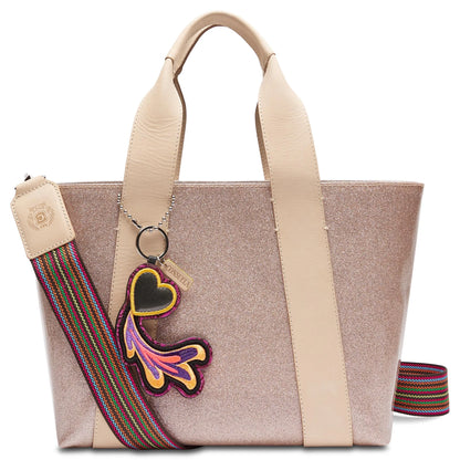 Consuela Emery Carryall featuring a champagne glitter exterior, natural leather handles, and a colorful woven crossbody strap.