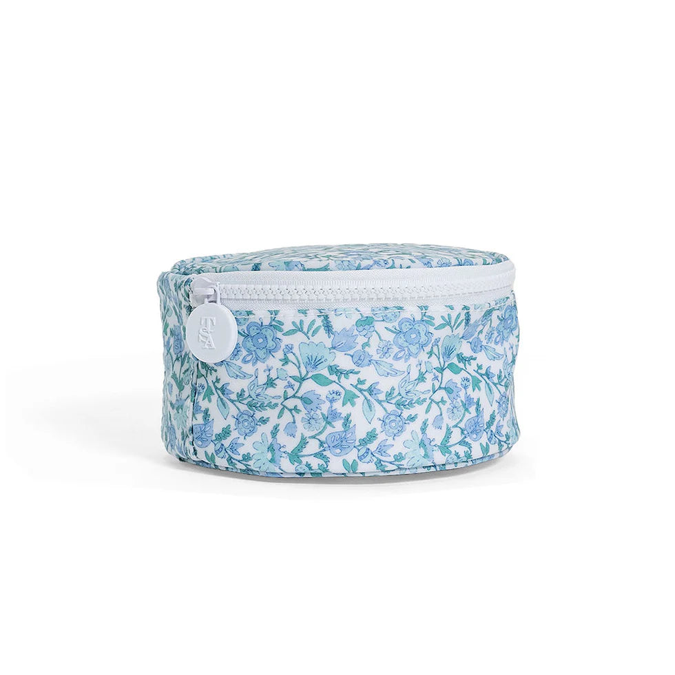 Round blue and white floral jewelry travel case with a white chunky zipper and interior elastic pockets.
