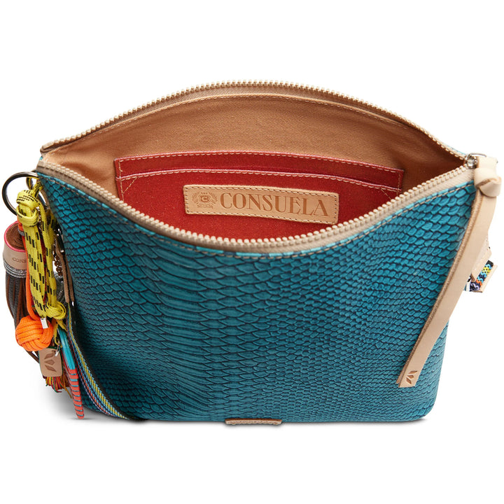 Consuela Indy Downtown Crossbody bag featuring a turquoise reptile-inspired textured exterior and a woven strap.