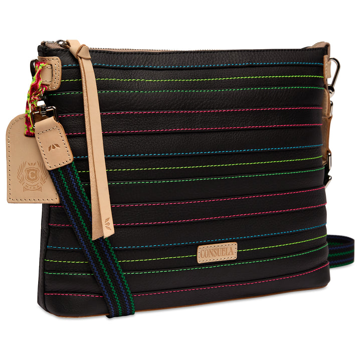 Three-quarter angled view of the Consuela Ray Downtown Crossbody in black leather with colorful contrast stitching, a leather hangtag, and Consuela nameplate.