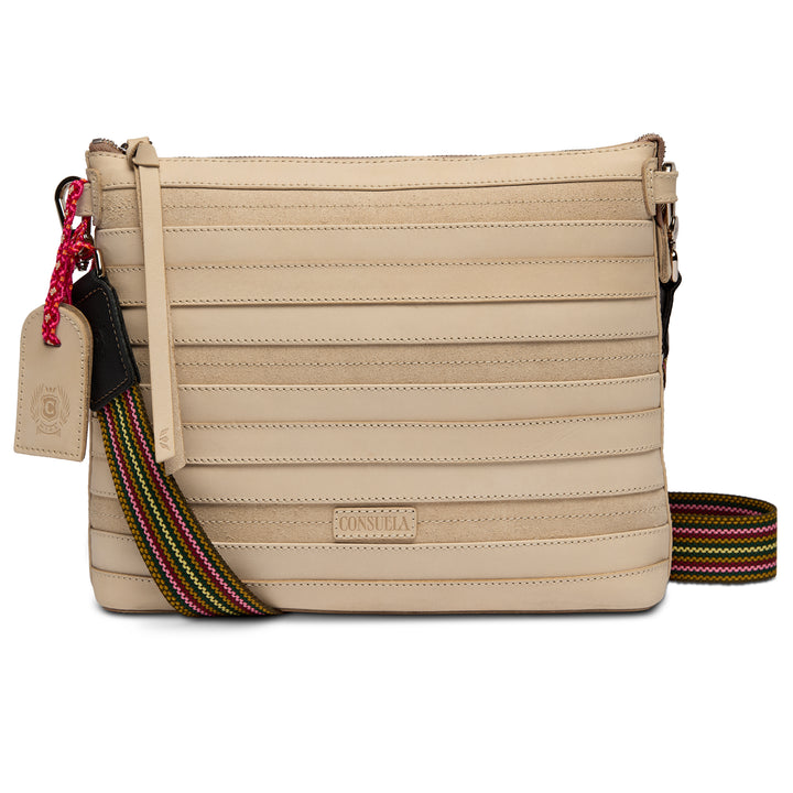 Front view of the Consuela Amina Downtown Crossbody in natural cream leather with a rainbow woven crossbody strap and leather hangtag.