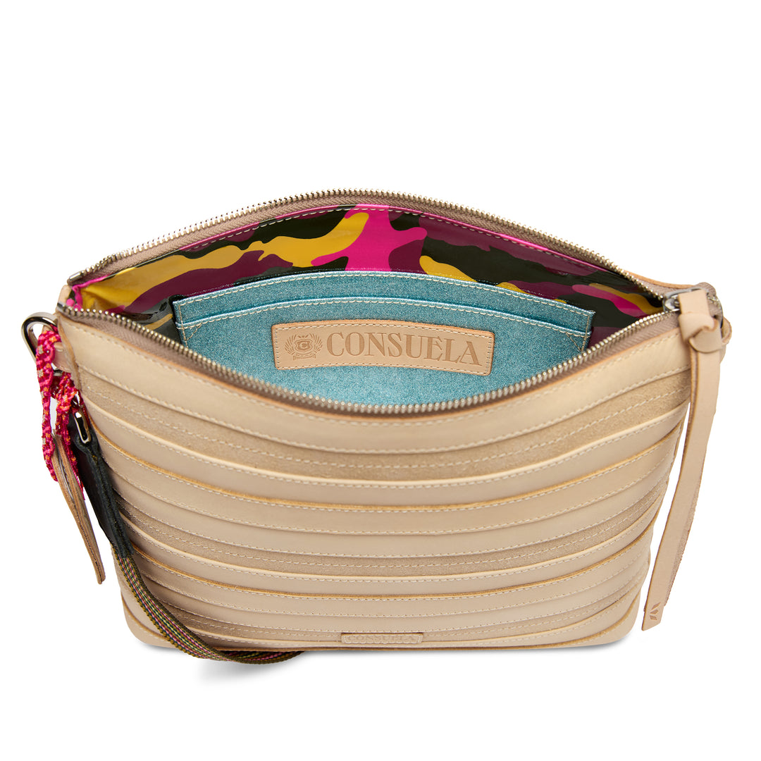 Interior view of the Consuela Amina Downtown Crossbody with a colorful camo-print lining, slip pocket, and teal Consuela-branded leather patch.
