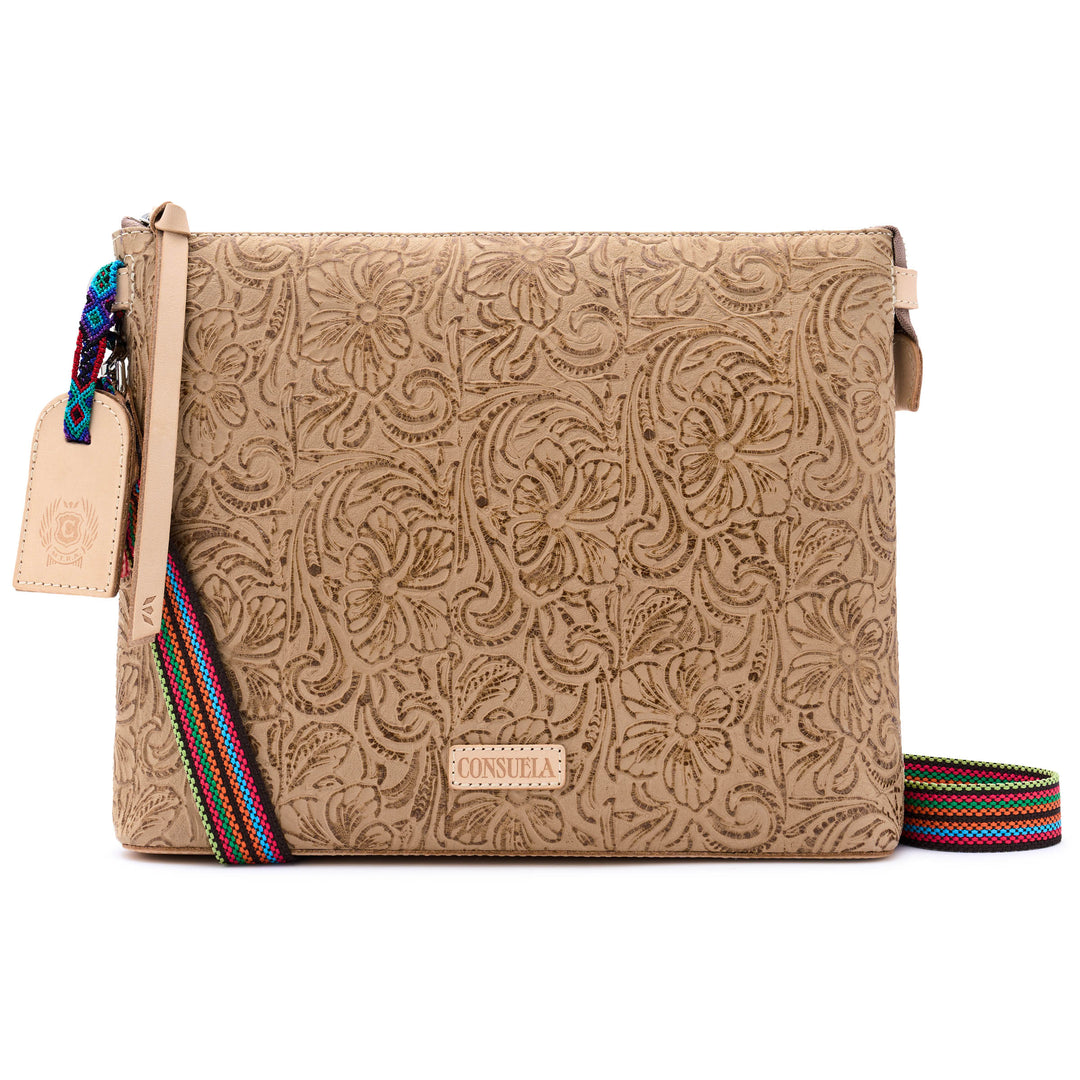 Front view of the Consuela Lawton Downtown Crossbody in tooled floral leather with the colorful strap extended and a Consuela nameplate.