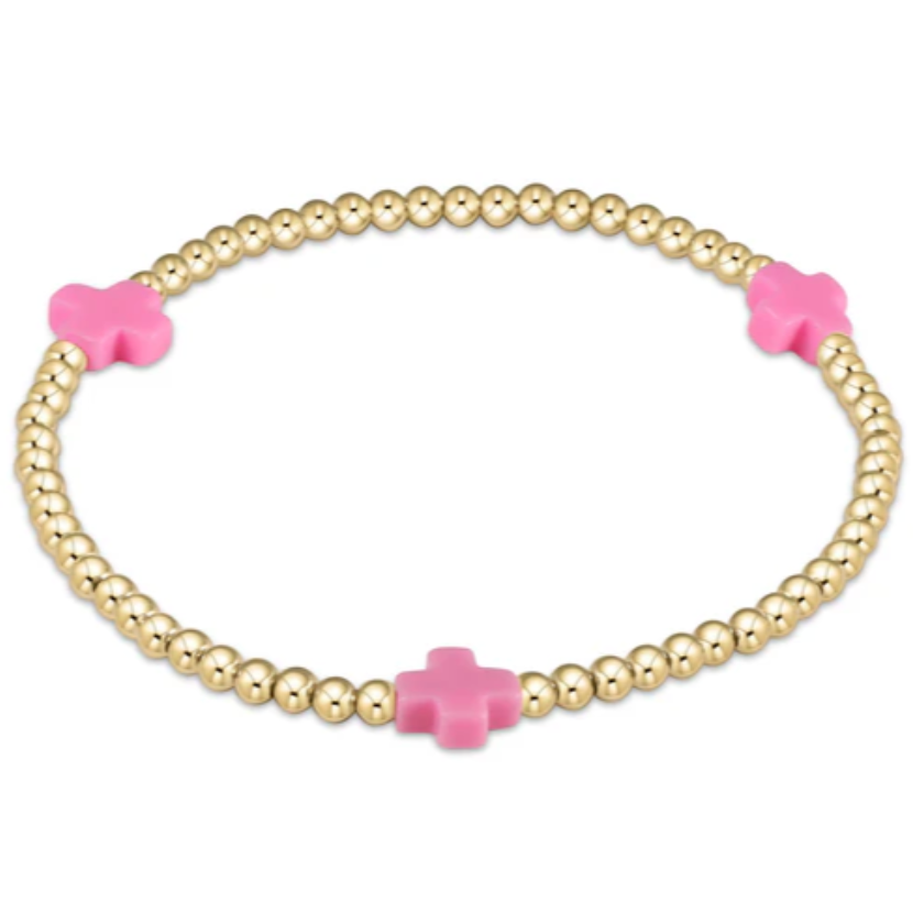 An enewton eGirl Signature Cross 3mm gold bead bracelet featuring three bright pink cross accents evenly spaced along a 14kt gold-filled stretch strand.