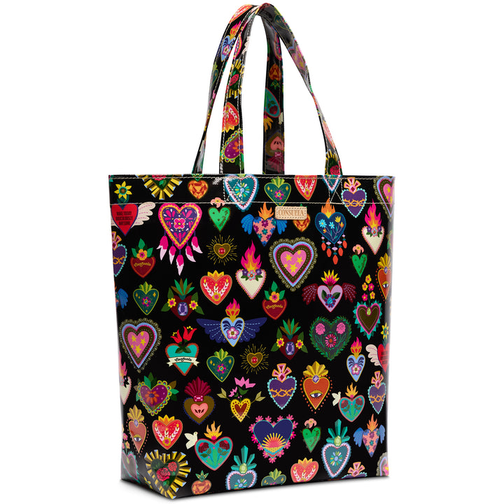 Three-quarter angled view of the Consuela Vida Grab n Go Basic black tote, showing its roomy side depth and all-over multi-color corazon heart print.