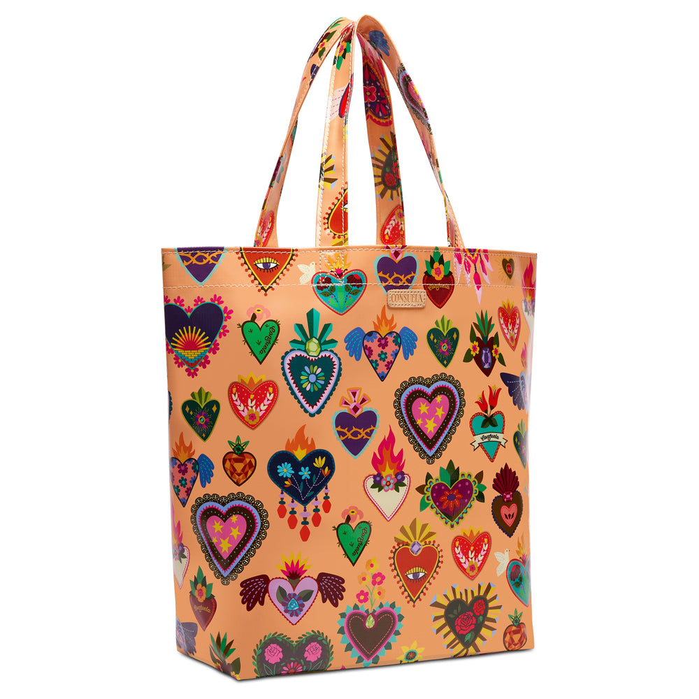 Three-quarter angled view of the Consuela Peach Grab n Go Basic, a glossy peach tote with an all-over colorful folk-art sacred-heart print and top handles.