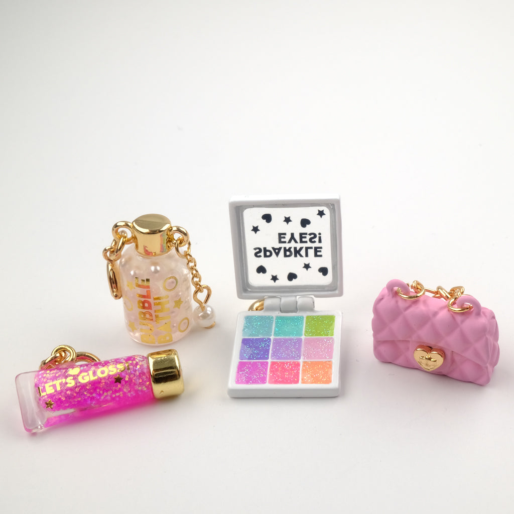 Charm It Gold Pink Purse charm in a flat lay of glam beauty kids charms