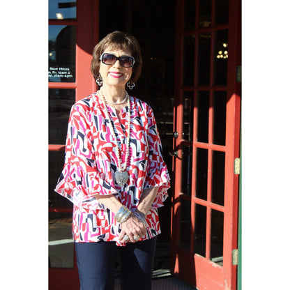 Woman in a colorful blouse standing next to a red door