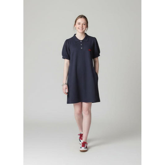 Person wearing a dark dress and red shoes standing on a sidewalk with brick steps and a store in the background.