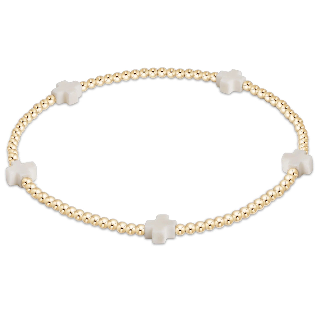 enewton Signature Cross Small 2mm Gold Bracelet in Off-White highlighting its soft neutral beads and 14k gold-filled cross pattern.