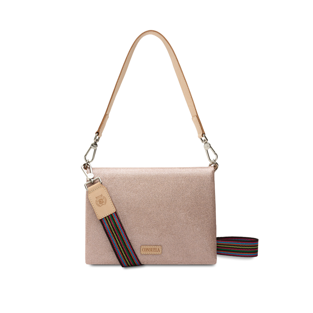 Consuela Emery Metro Crossbody in blush metallic glitter, front view with a natural leather strap and rainbow woven crossbody strap on a light background.