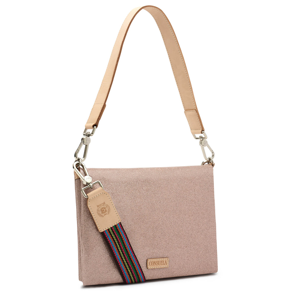 Three-quarter angled view of the Consuela Emery Metro Crossbody in blush metallic glitter with polished silver hardware and a rainbow woven strap.