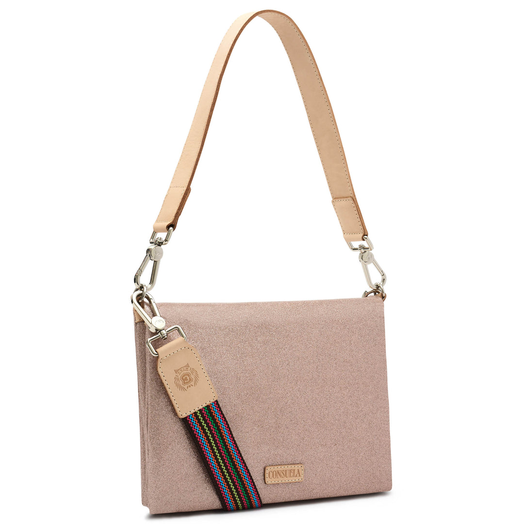 Three-quarter angled view of the Consuela Emery Metro Crossbody in blush metallic glitter with polished silver hardware and a rainbow woven strap.