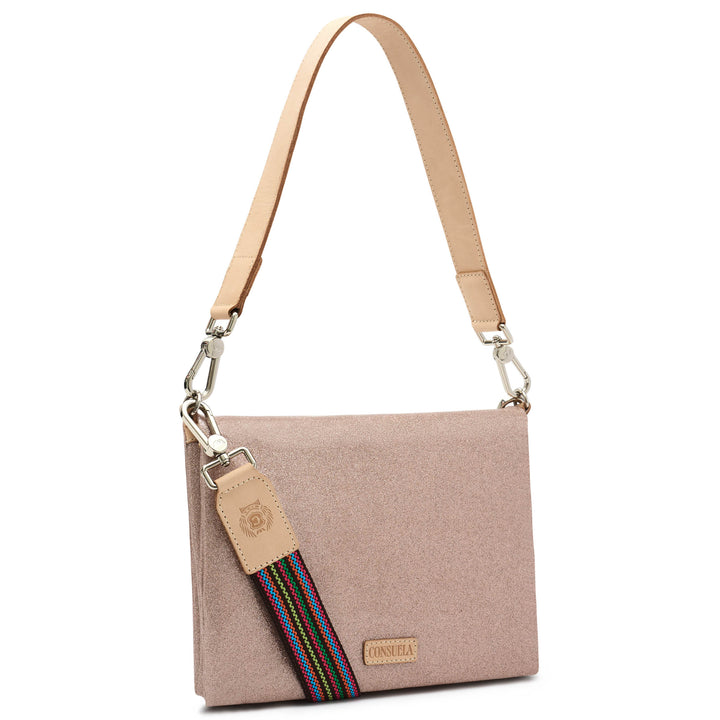Three-quarter angled view of the Consuela Emery Metro Crossbody in blush metallic glitter with polished silver hardware and a rainbow woven strap.
