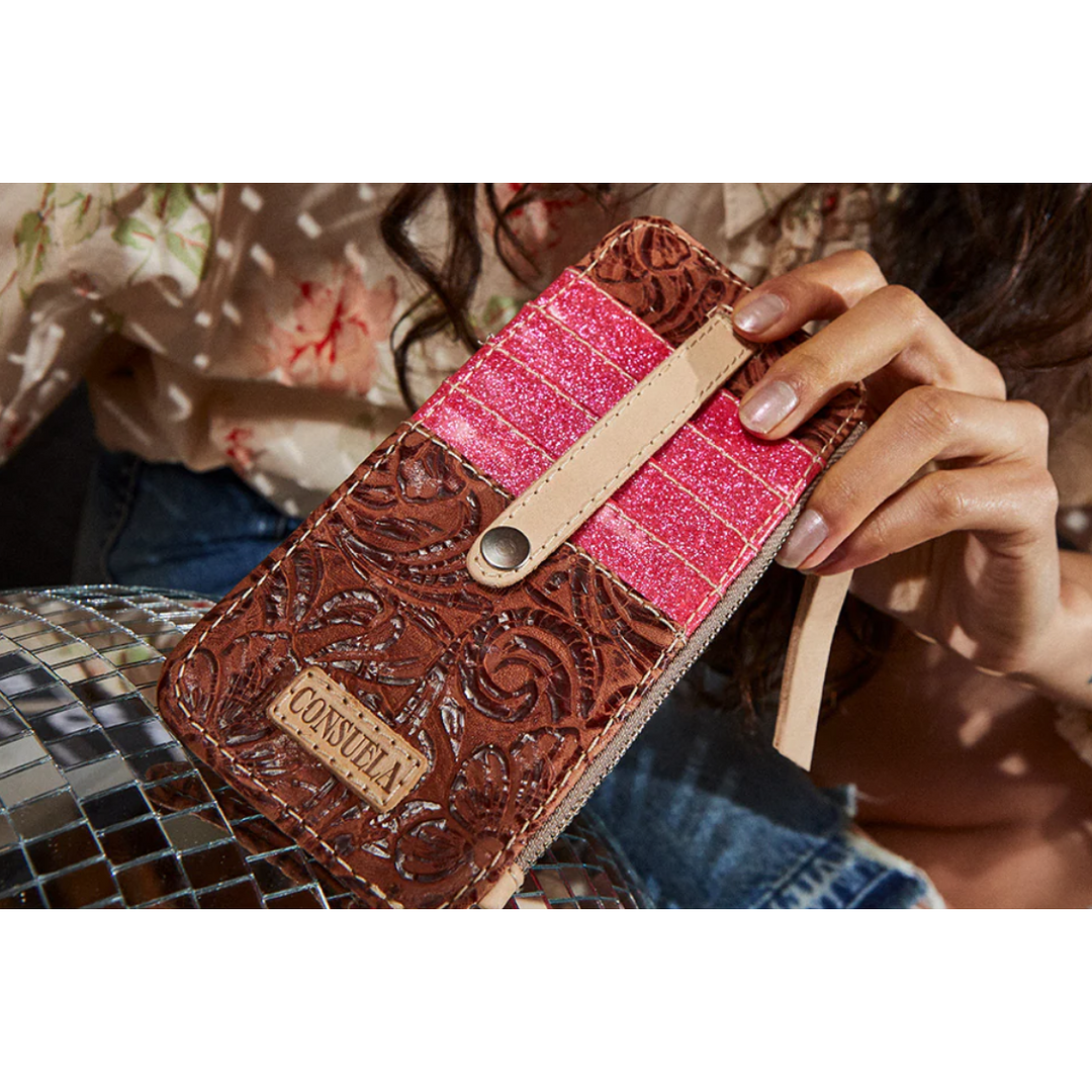 Consuela Sally Card Organizer featuring a brown tooled leather exterior, hot pink glitter detailing, and a natural leather strap closure.
