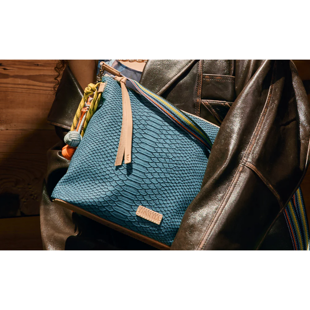 Consuela Indy Downtown Crossbody bag featuring a turquoise reptile-inspired textured exterior and a woven strap.