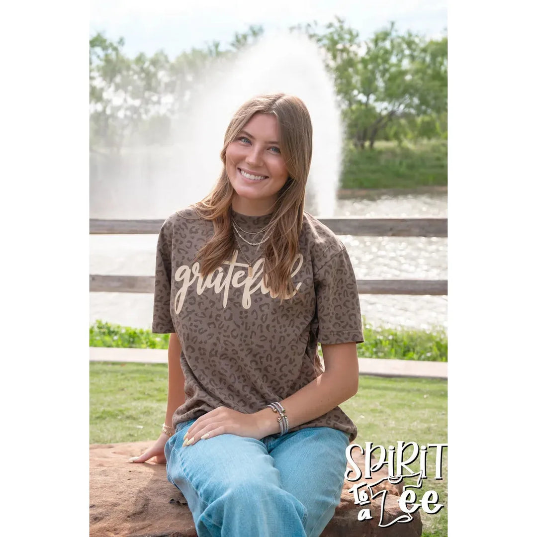 Model smiling outdoors wearing the Spirit to a Tee Grateful oversized brown animal print Thanksgiving graphic t-shirt.